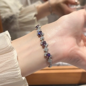 Detail of silver bracelet featuring oval purple and blue zircons on a model's wrist