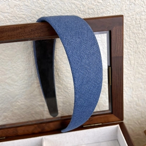 Détail d'un serre-tête en denim bleu avec texture pailletée sur un coffret à bijoux en bois