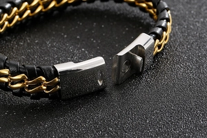 Detail of the magnetic buckle on a black braided leather and gold chain men's bracelet