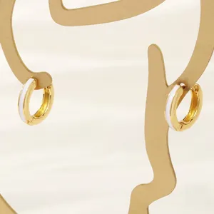 Detail of 18K gold plated hoop earrings with white enamel on a creative artistic display