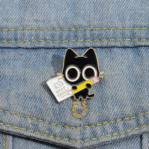 Detailed view of an enamel black cat pin with Keep Trying text on denim jacket