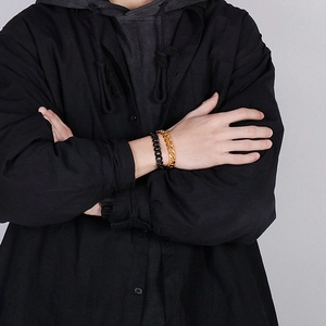 Detail of model wearing double layered Cuban chain bracelets in gold and black finish