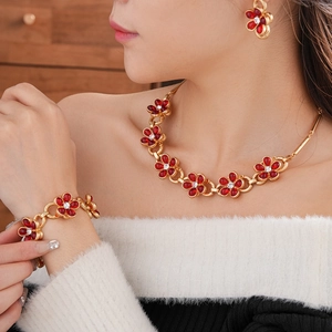 Detailed view of red floral necklace and bracelet set with crystals on gold metal
