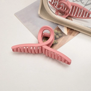 Close-up of pink matte hair claw clip showing textured finish and spring mechanism