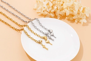 Polished gold and silver bracelets with heart and key charms on a decorative ceramic dish