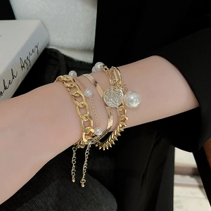 Detail of layered gold chain bracelet with toggle clasp and imitation pearl accents