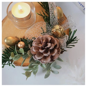 Detail view of a Christmas wooden candle holder with pine cones, golden bells and swan lace
