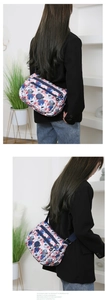 Women's colorful floral nylon crossbody bag shown worn by a model in a modern room
