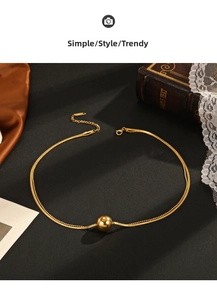 Detailed view of layered gold snake chain and beaded necklace with round metal bead pendant