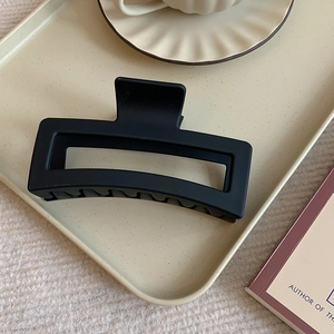 Detail of matte black square hair claw clip placed on a decorative beige polka dot plate