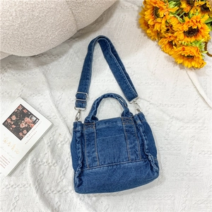 Detail of blue washed denim crossbody bag with adjustable strap and retro pleat design