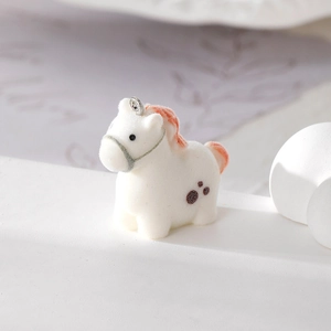 Macro detail of flocked white pony charm with pink mane and silver metal ring loop
