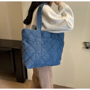 Détail du sac cabas en denim bleu montrant le matelassage en losanges et la bandoulière large