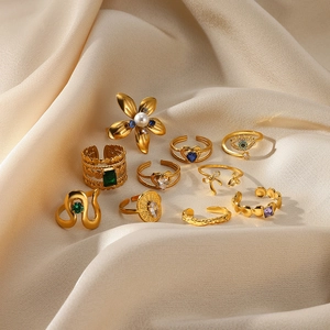 Detailed view of assorted gold rings with flower and pearl charms on silk background