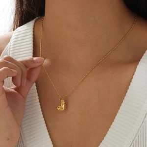 Gold heart pendant necklace with beaded chain on model wearing white v-neck sweater