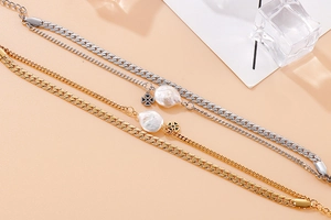 Detailed macro view of gold and silver layered bracelet with baroque pearl and cross charm