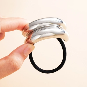 Detailed view of a silver C-shaped metal hair cuff with a black elastic tie
