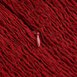Macro detail of red ruched lace fabric with a matching invisible zipper closure