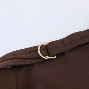 Nahaufnahme der braunen Midi-Kleid-Stoffstruktur mit goldener D-Ring-Schnalle