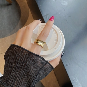 Minimalist wide golden ring with hammered lava texture and irregular wavy edges on hand