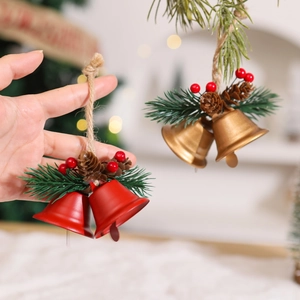 Christmas metal bells with pine cones and red berries hanging on a festive tree branch