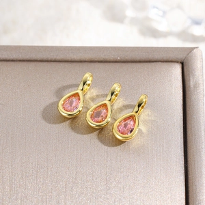 Detailed view of three 18k gold plated teardrop pendants with pink zircon crystals