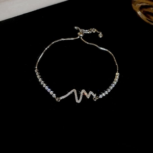 Macro shot of adjustable silver bracelet with zircon-encrusted heartbeat design on black background