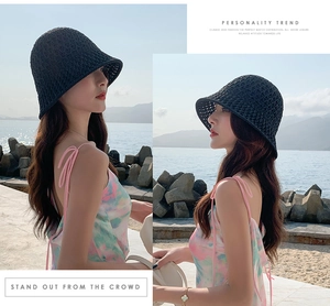 Détail d'un chapeau cloche en maille ajourée noire porté par un mannequin à la plage