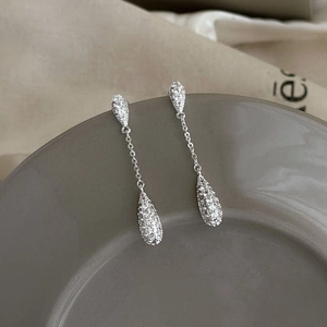 Detailed view of silver water drop earrings with sparkling pavé zircons on a tray