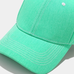 Detail of mint green cotton baseball cap showing reinforced brim stitching and eyelet