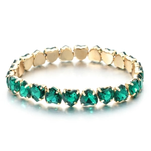 Detail view of heart-cut emerald green crystals set in a golden claw setting bracelet