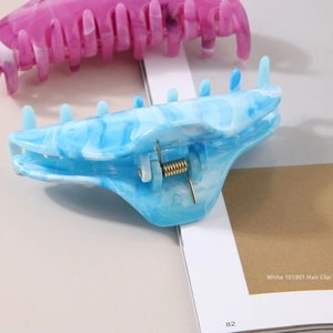 Large marble pattern hair claw clips in blue and pink on a magazine background