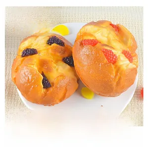 Close-up of artificial muffin models with berries on a white ceramic plate