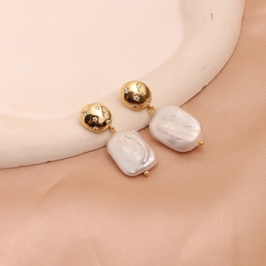 Baroque pearl drop earrings with golden star relief on elegant champagne satin