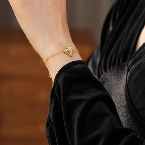 Gros plan d'un bracelet doré avec perles florales et cristaux sur poignet