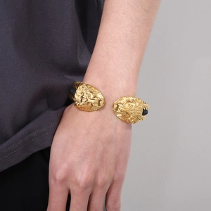 Detailed close-up of a men's wire bracelet featuring two golden lion head charms