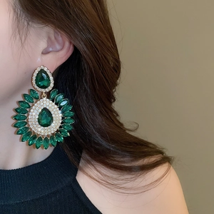 Detailed view of luxury emerald drop flower earring with sparkling rhinestones on model