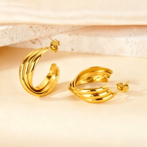 Detailed close-up of triple-layered gold geometric earrings on marble surface