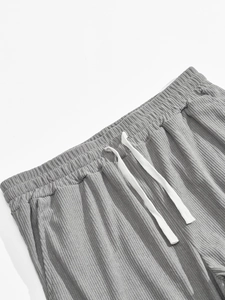 Detail of grey corduroy pants showing elastic waistband and white braided drawstring