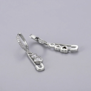 Detail of S925 silver huggie earrings with safety pin pendant and heart zirconia