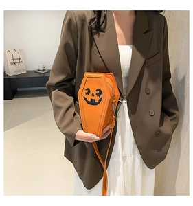 Detail of a coffin-shaped orange crossbody bag with a black pumpkin smile print design