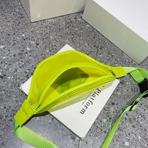 Detail view of neon yellow clear PVC waist bag with adjustable strap on white pedestals