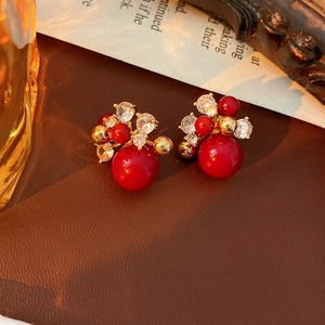 Detail of red cluster earrings with zircons and pearls on a vintage leather surface