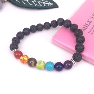 Detalle de cuentas de lava volcánica y siete piedras de chakra en una pulsera elástica