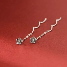 Vue macro du pendentif fleur en argent avec crochet d'oreille sur fond marron