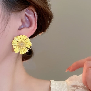 Detail of a 3D yellow daisy earring with raffia petals on a model for a beach vacation style