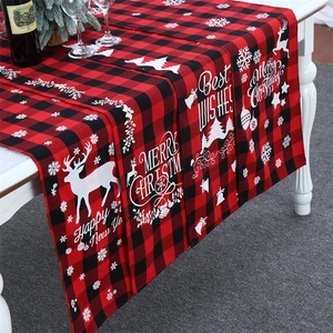 Detail of red and black buffalo plaid Christmas table runner with festive elk and snowflake prints