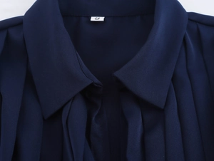 Macro detail of dark blue satin dress neckline with pleats and size label showing S