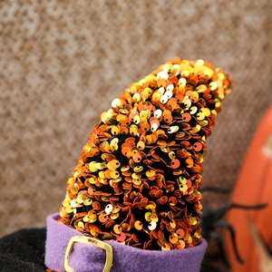 Close-up of Halloween witch hat featuring orange sequins, purple felt band and gold buckle