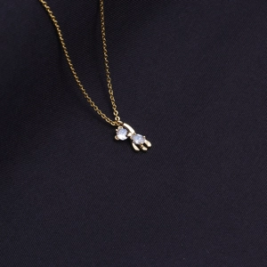 Close-up of gold-plated bear pendant necklace with two sparkling clear gemstones
